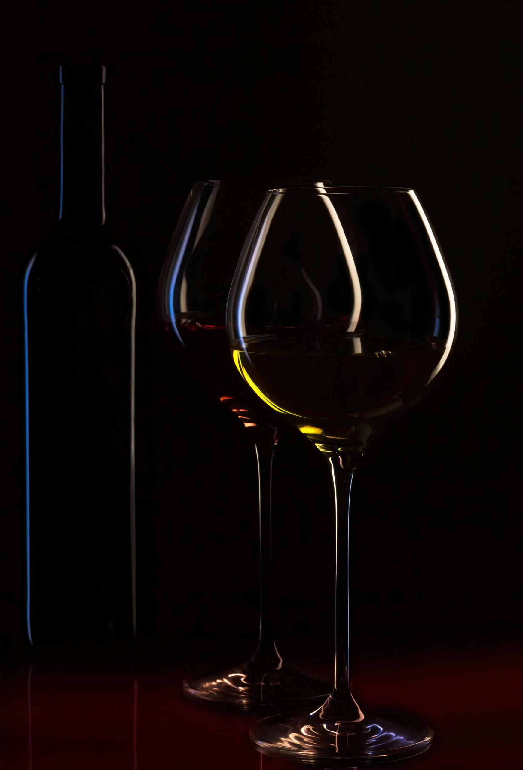 Elegant silhouette of wine glasses with a bottle in moody lighting, perfect for a classy atmosphere.