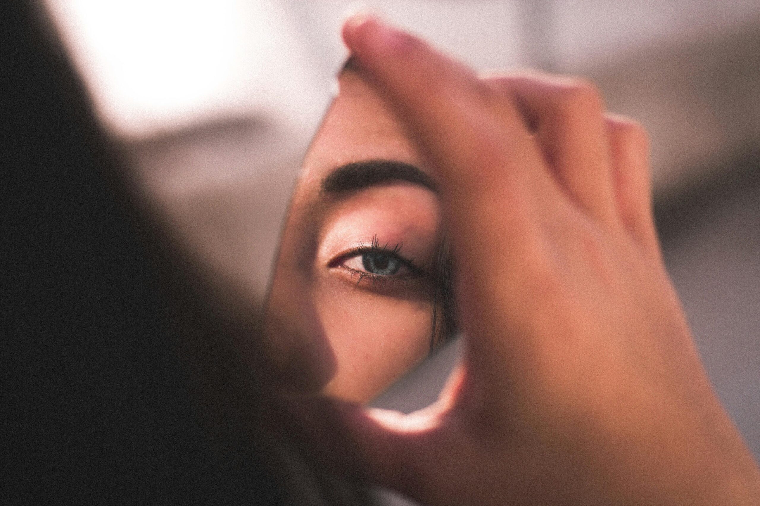 A captivating image of a woman's eye reflected in a broken mirror piece with soft lighting.