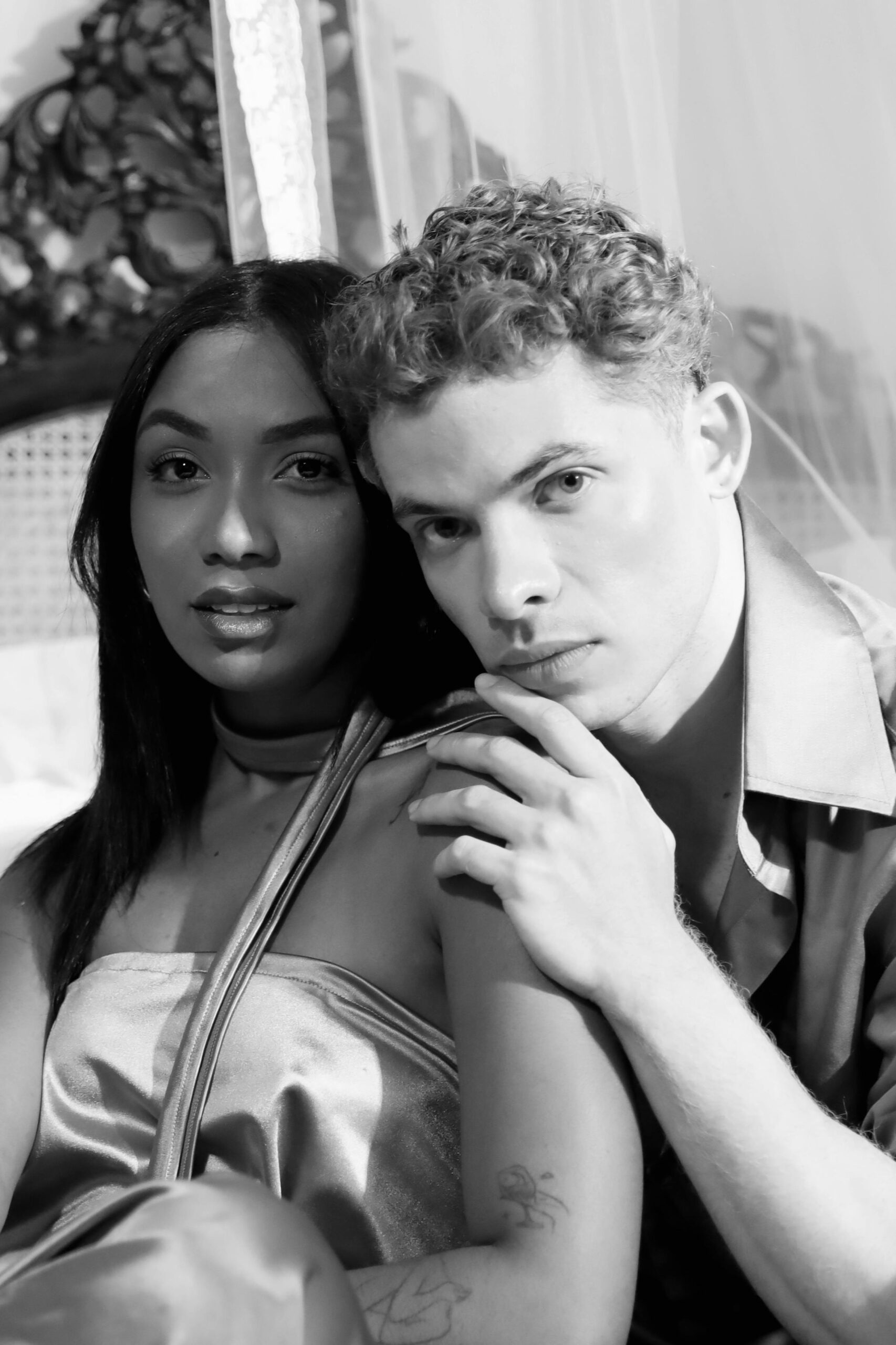 A close-up, artistic black and white portrait of a couple sharing an intimate moment indoors.