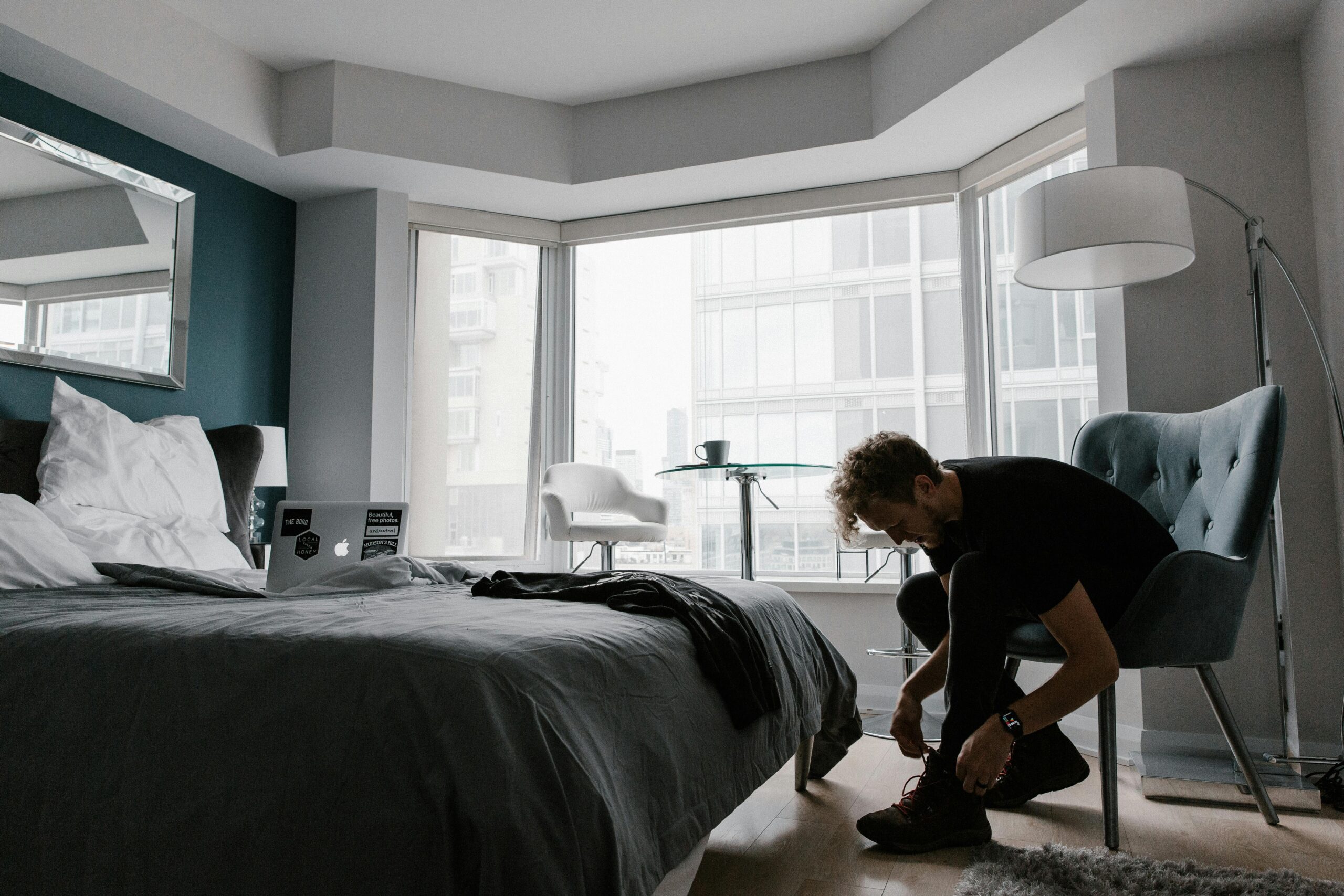 Contemporary hotel room with a man tying shoes in a bright Toronto setting.